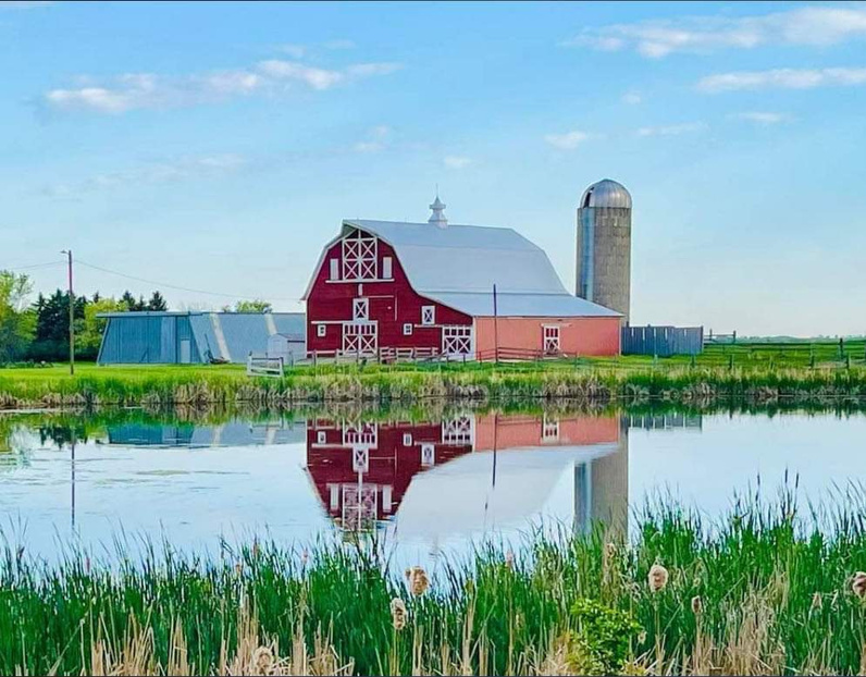 a red barn is reflected in a body of water